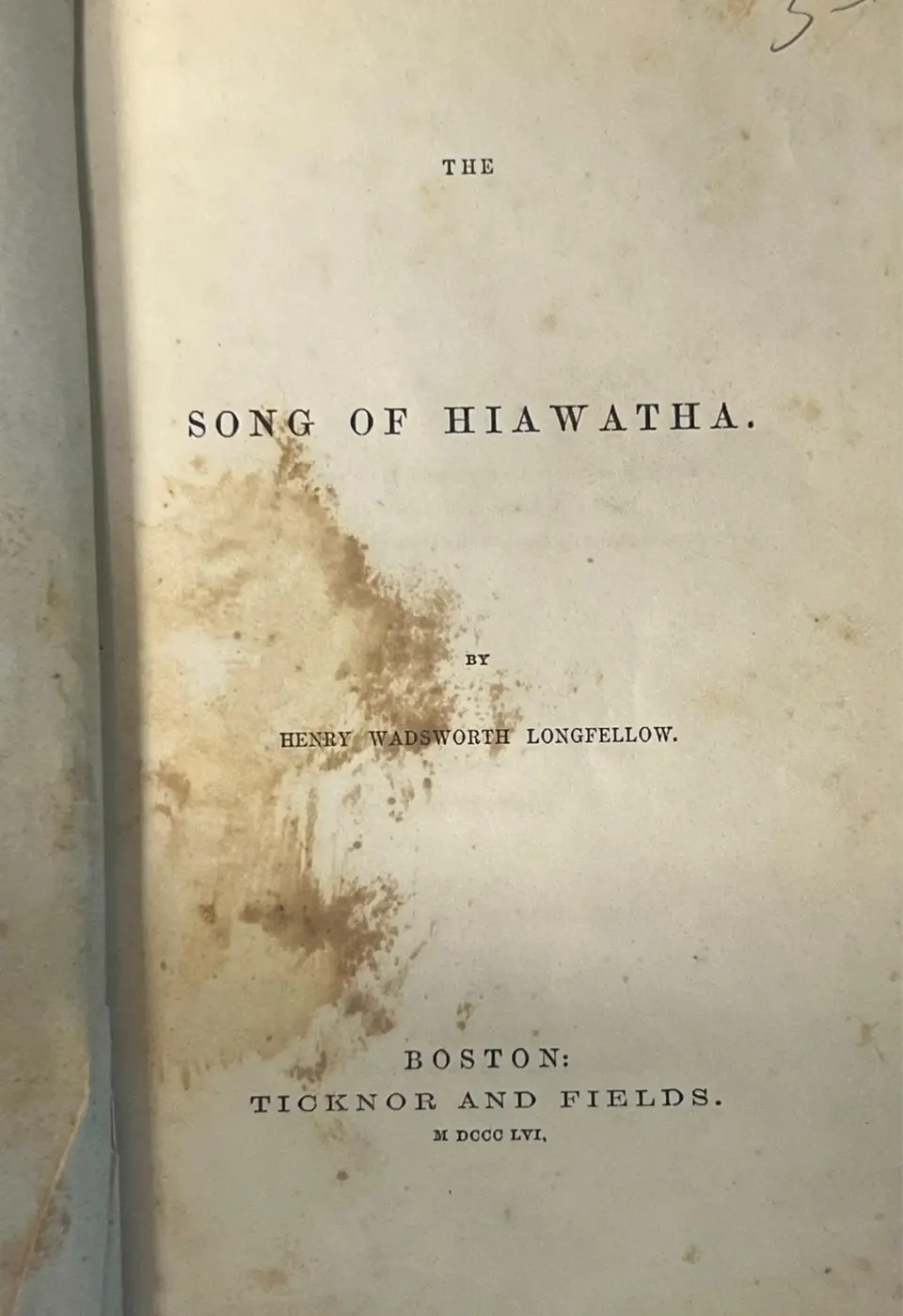Title page of The Song of Hiawatha, Ticknor and Fields 1856, with a large brown water stain across the author's name