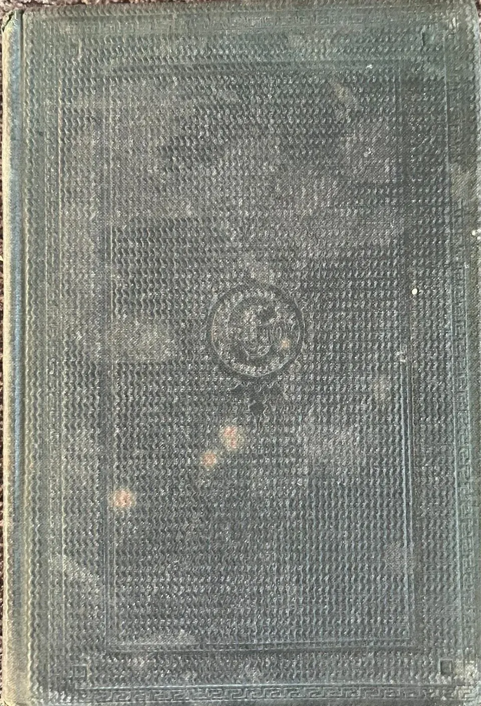Dark green cloth cover of The Old Merchants of New York City, blind stamped with a Greek key border and central medallion, with no title lettering