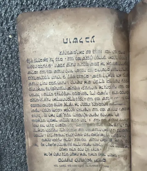 A straight-on page of the book showing a large heading in East Syriac script above a full block of hand-written text
