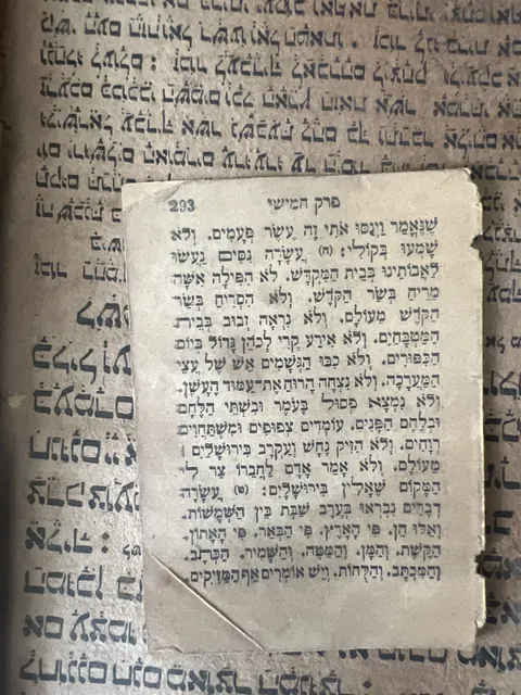 Close view of one loose printed Hebrew leaf, page 293, headed Chapter Five, lying on the hand-written Syriac book